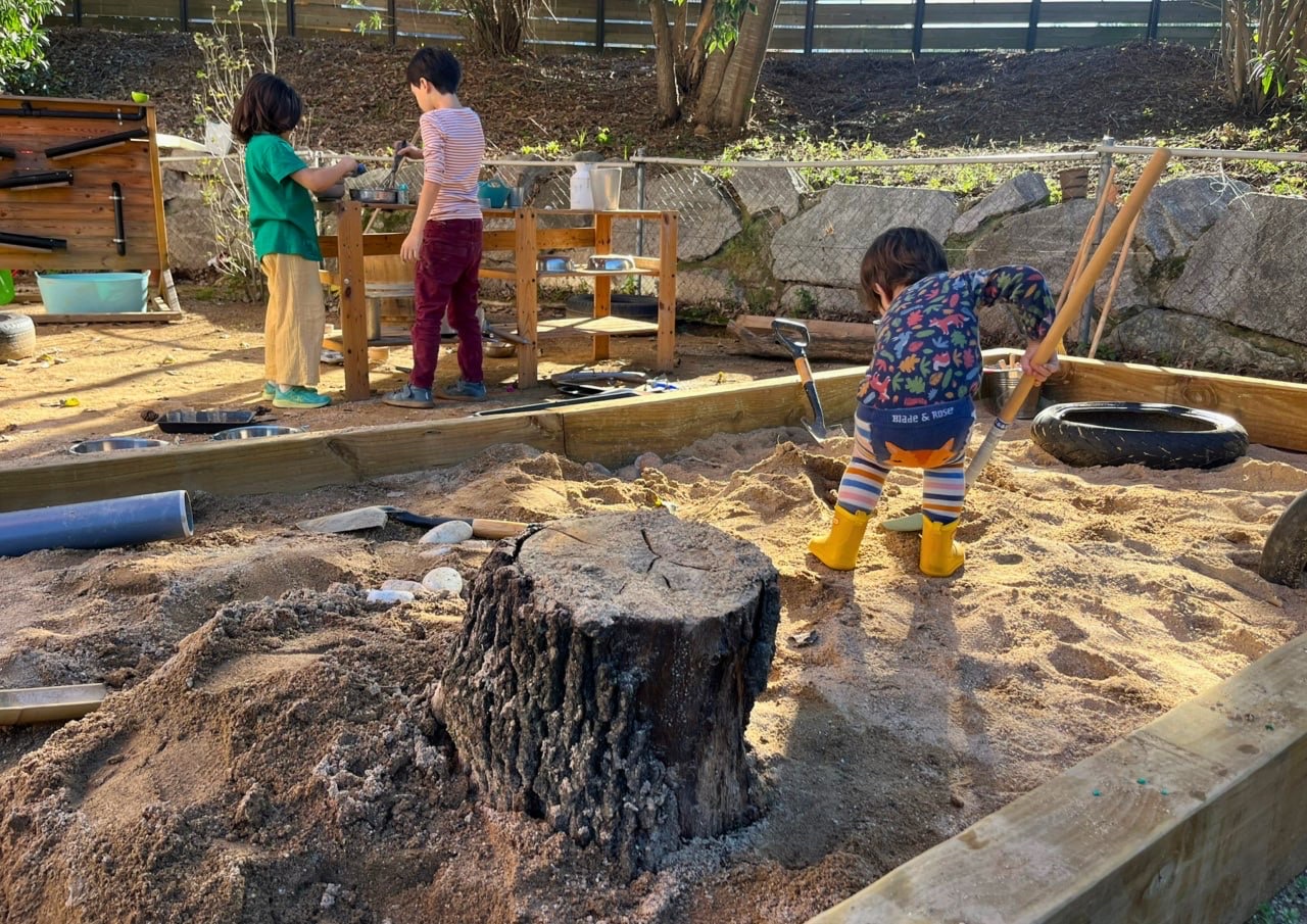 Infants jugant amb sorra i estris al jardí d’El Refugi